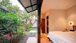 A bedroom with a bed, a nightstand, and a wall-mounted lamp. - MRUDA FARMSTAY (Dahanu)