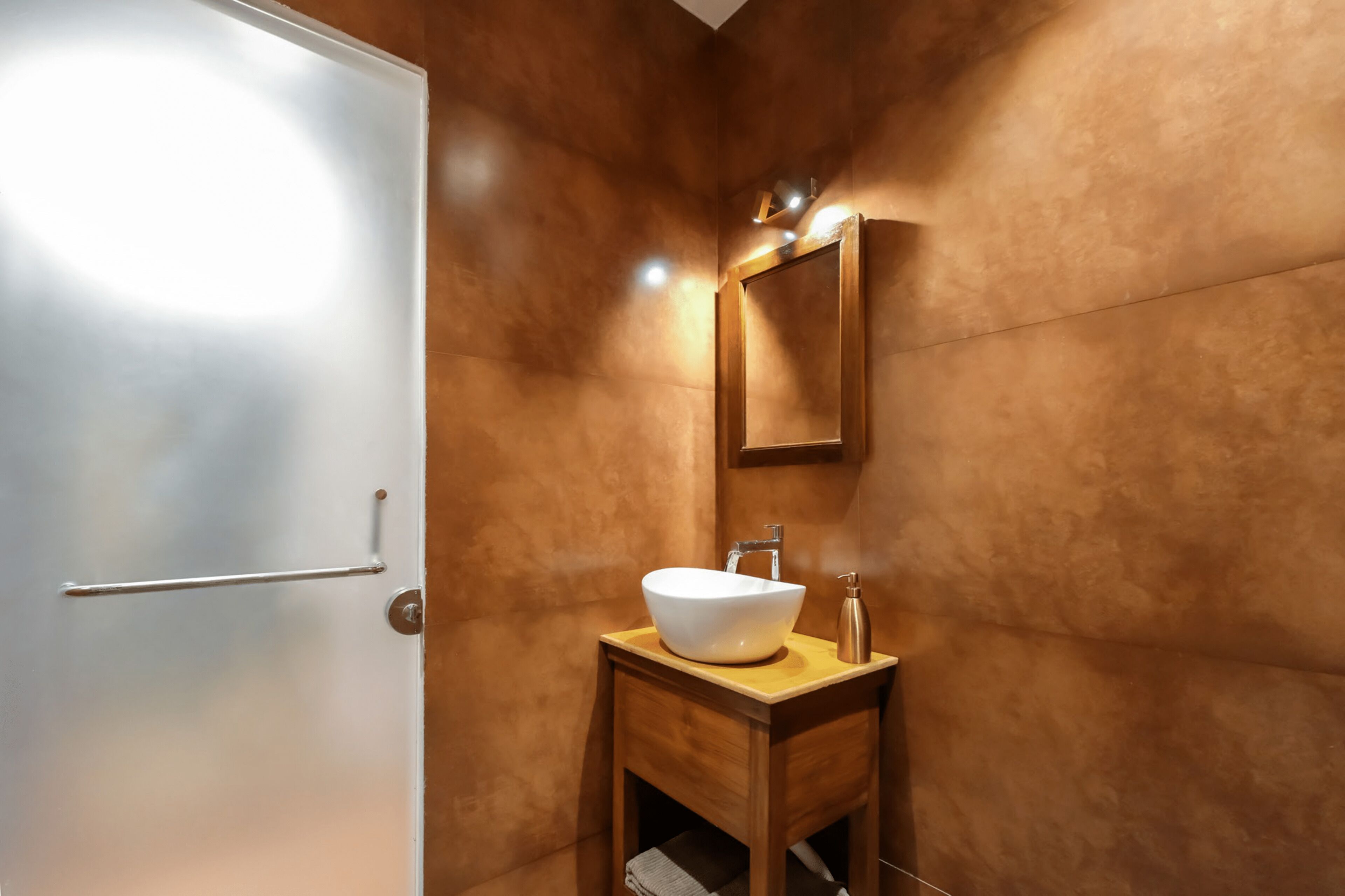 A bathroom with a white sink, wooden vanity, and a mirror.
