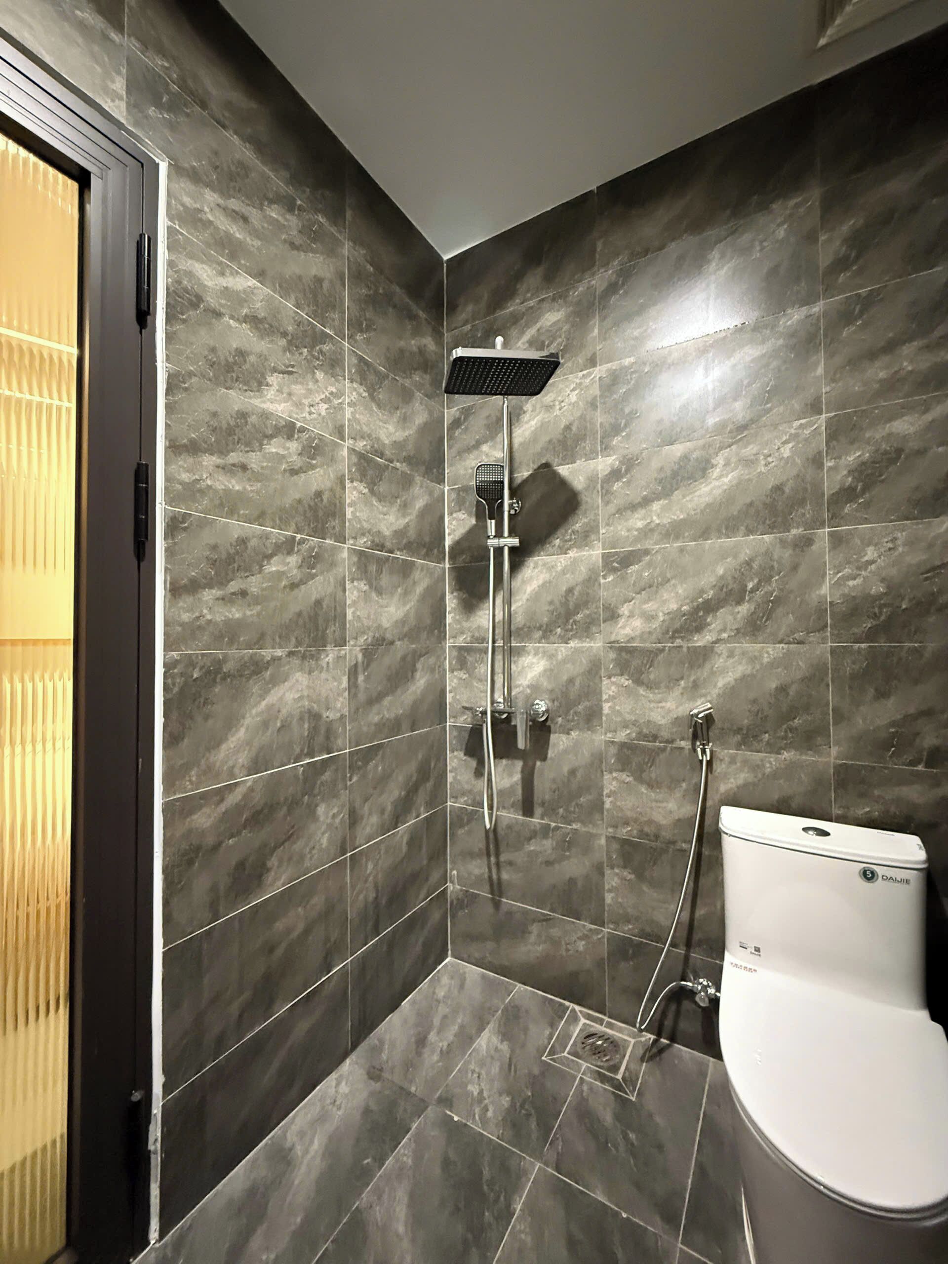 Un baño moderno con ducha, inodoro y toallero de pared.