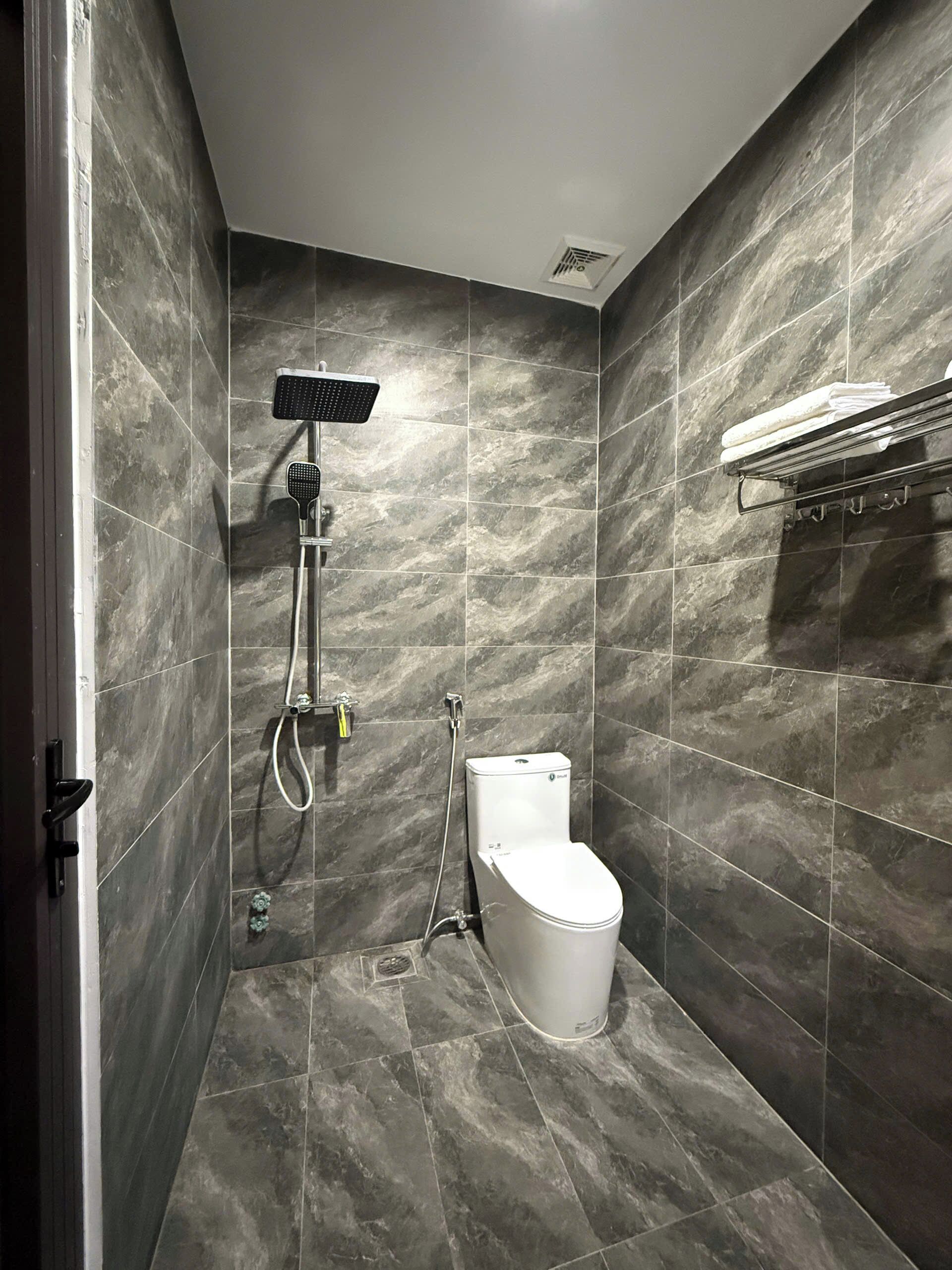 Een moderne badkamer met douche, toilet en handdoekrek.