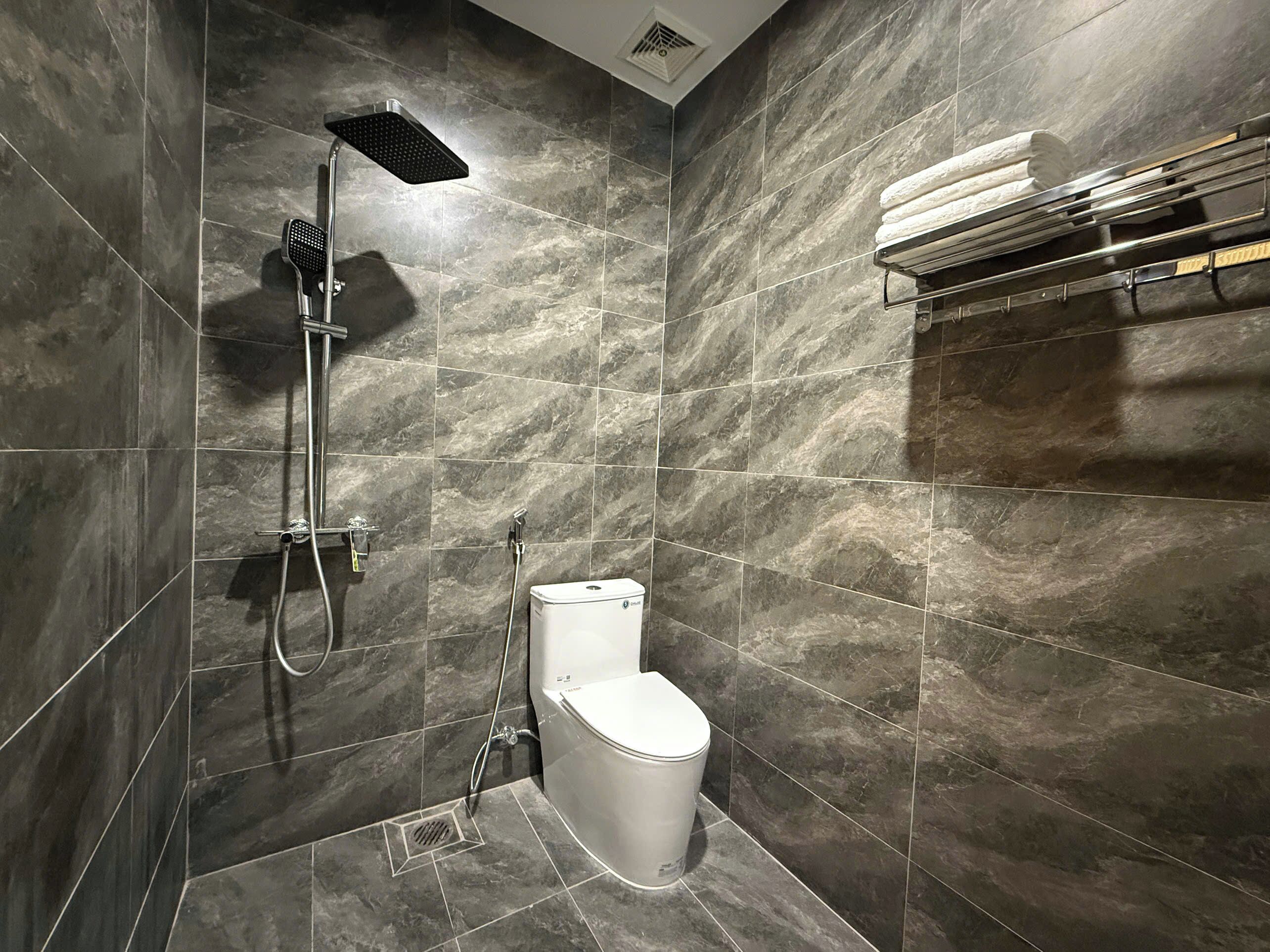 A modern bathroom with a shower, toilet, and towel rack.