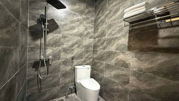 A modern bathroom with a shower, toilet, and towel rack.