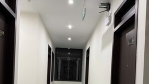 A corridor with a tiled floor, dark wooden doors, and a ceiling with recessed lighting. - Bacnam Quang Ngai Hotel (Nghia Lo)