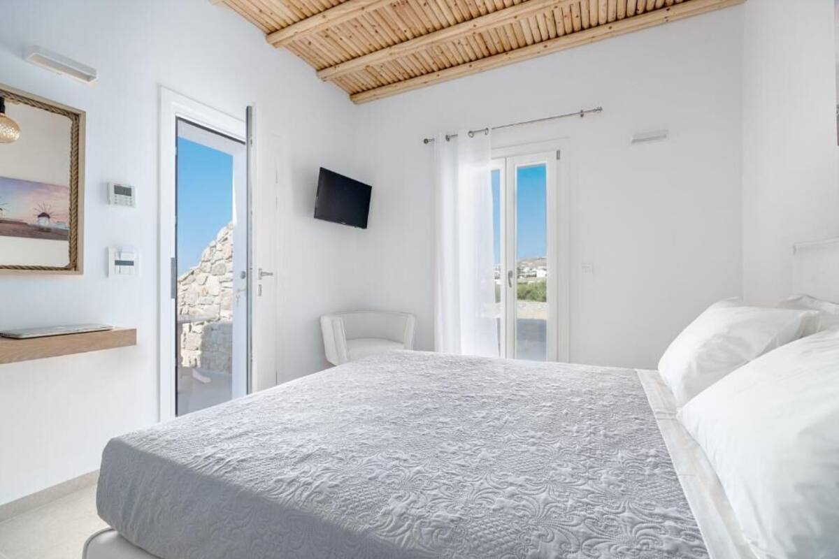Une chambre avec un lit, une chaise, une télévision et une vue sur l’extérieur.