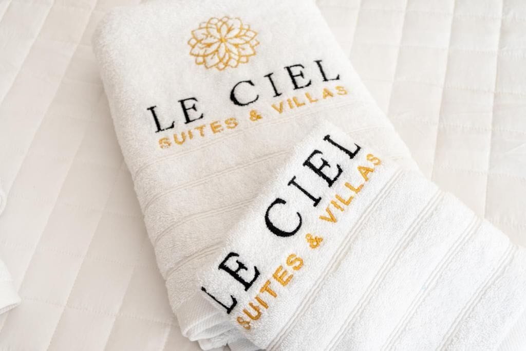 A folded towel with embroidered text reading "LE CIEL SUITES & VILLAS".
