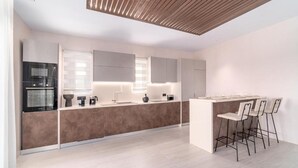 Una cocina moderna con una isla central, taburetes de bar y electrodomésticos integrados.