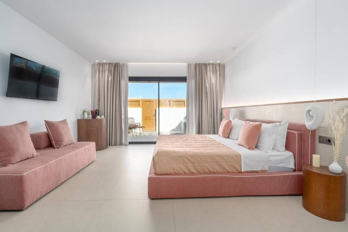 Une chambre moderne avec un grand lit, un canapé, une télévision et un balcon agrémenté de rideaux.