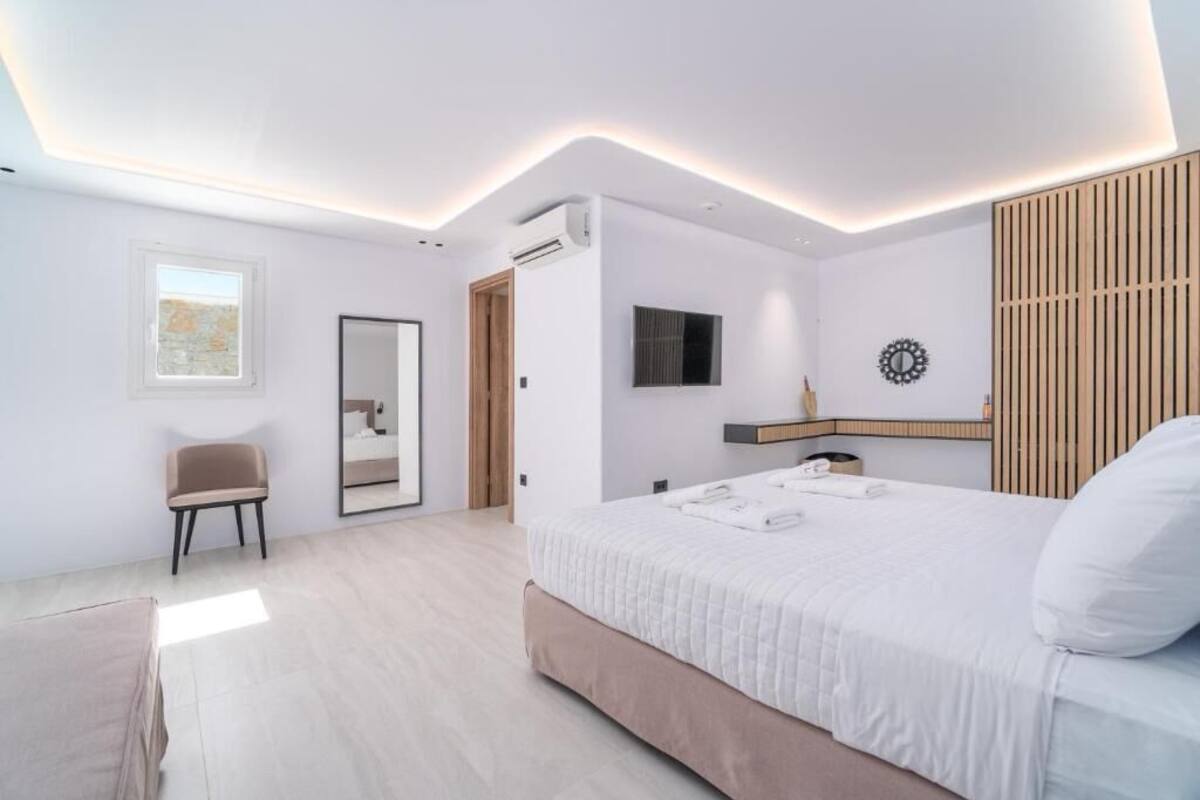 Une chambre moderne avec un grand lit, une chaise, un miroir et une petite table.