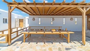 Una pérgola de madera con suelo de piedra y una mesa de madera dispuesta para comer.
