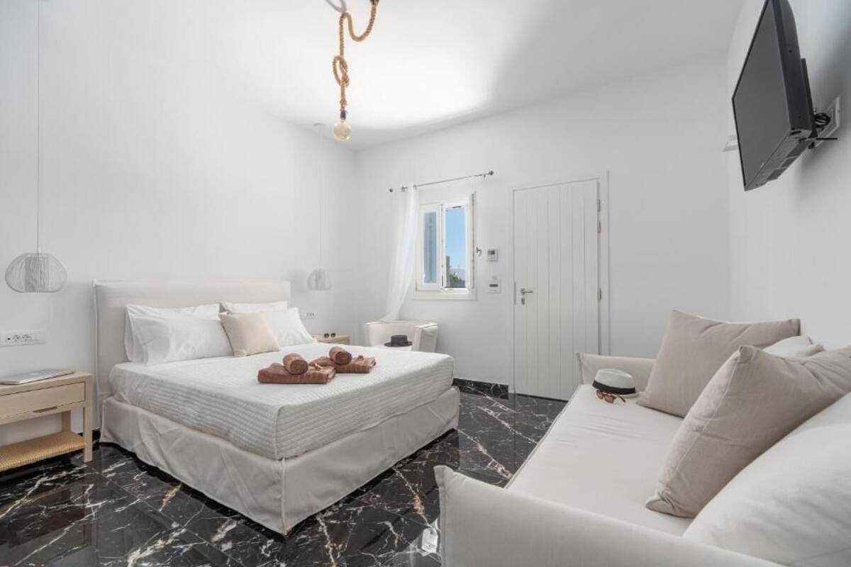 Une chambre à coucher moderne avec un lit, un canapé, une télévision et une fenêtre.
