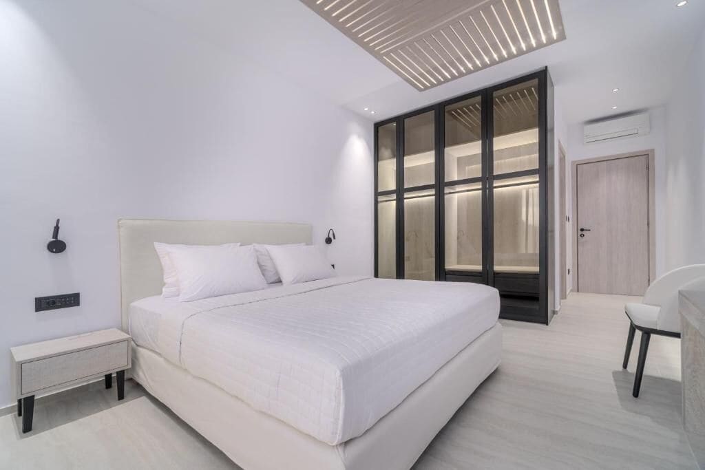 Een moderne slaapkamer met een groot bed, nachtkastjes, een kledingkast en een stoel.