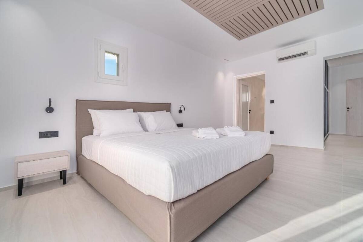 Une chambre moderne avec un grand lit, des tables de chevet et un luminaire fixé au plafond.
