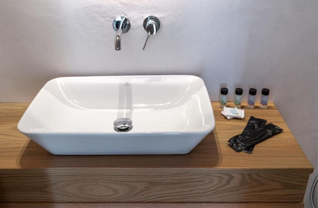 Ein weißes, rechteckiges Waschbecken mit zwei Wasserhähnen auf einer Holzauskleidung.