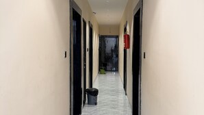 A corridor with marble flooring, beige walls, and black doors. - hotel shivlok inn (Ujjain)