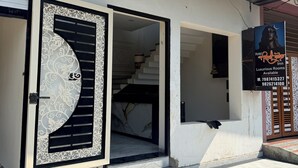 A hotel entrance with a decorative gate, a staircase leading to the interior, and a signboard advertising luxurious rooms. - hotel shivlok inn (Ujjain)