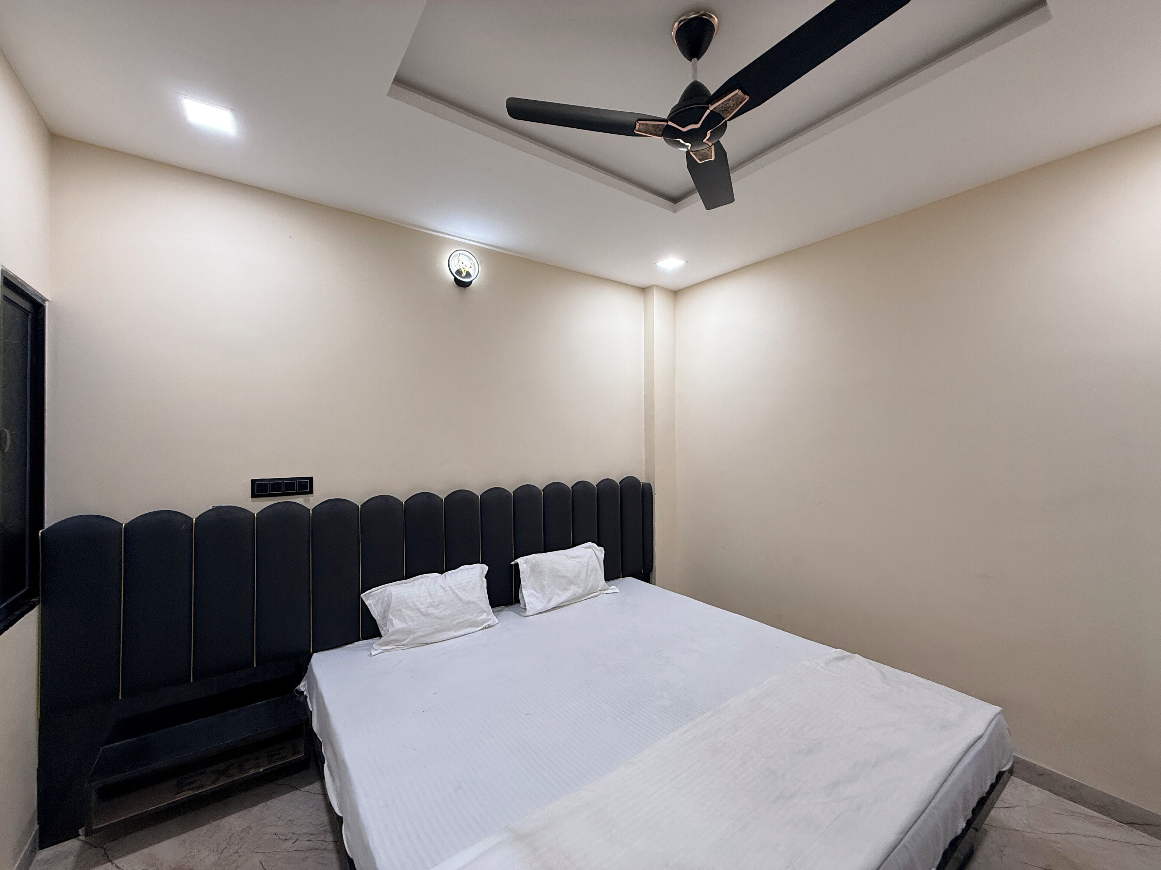 A bedroom with a bed, a ceiling fan, and recessed lighting.