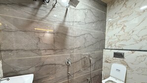 A bathroom with a marble wall, a sink, a toilet, and a shower. - hotel shivlok inn (Ujjain)