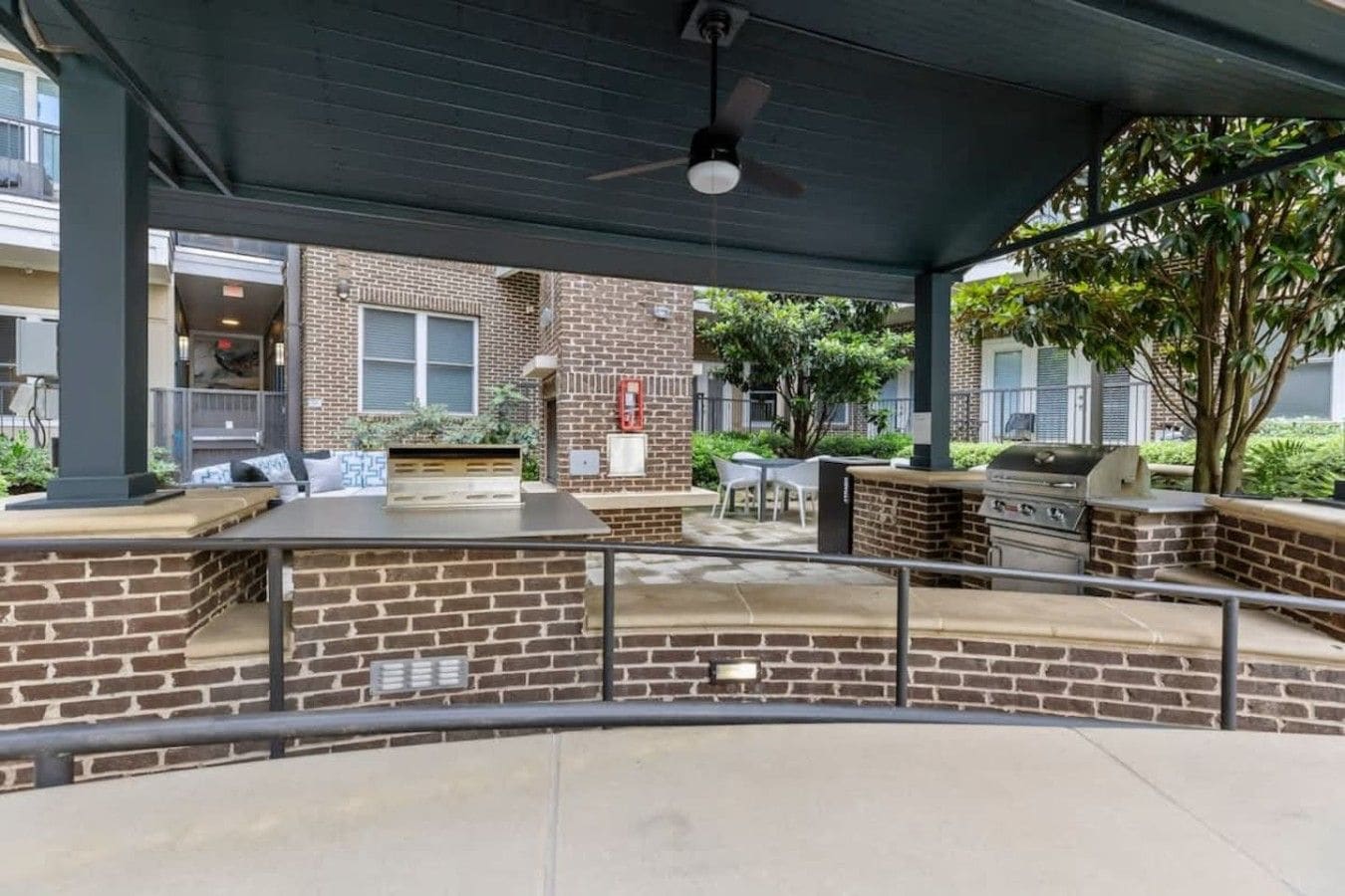 An outdoor patio area with a brick wall, a grill, and seating.