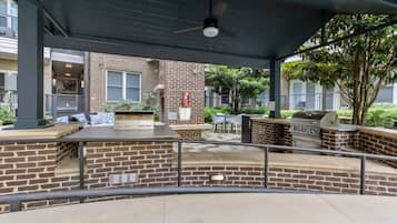 An outdoor patio area with a brick wall, a grill, and seating.