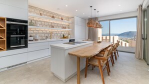 Une cuisine moderne dotée d’un îlot central, d’un four encastré et de meubles de cuisine blancs.