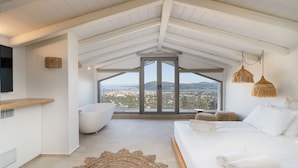 Une chambre moderne avec un grand lit, une baignoire et une vue sur la ville.