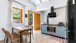 A modern kitchen with a black refrigerator, a built-in oven, and a wooden door. - Villa Semipuella (Lefkada)