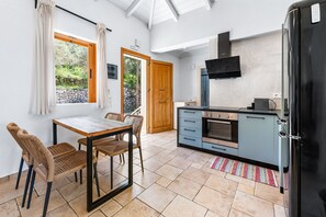 A modern kitchen with a black refrigerator, a built-in oven, and a wooden door. - Villa Semipuella (Lefkada)