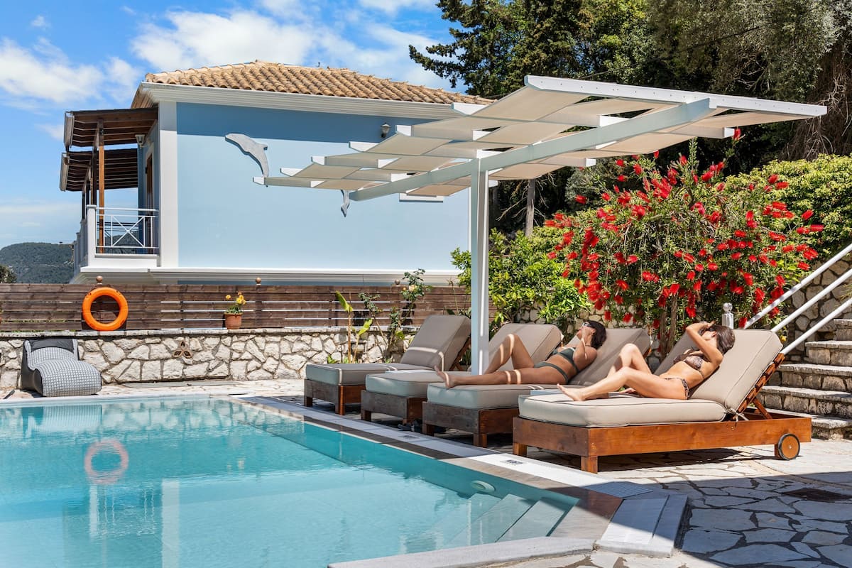 Un espace piscine comprenant des chaises longues, une pergola et un mur en pierre.
