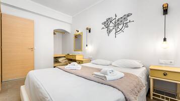 Quarto de hotel bem organizado, com cama, mesas de cabeceira, guarda-roupa e espelho.