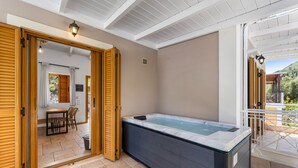 A spa area with a hot tub, wooden doors, a table with chairs, and a view of the outdoors. - Villa Semipuella (Lefkada)