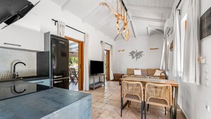 A modern kitchen with a built-in refrigerator, a dining area with wicker chairs, and a flat-screen TV. - Villa Semipuella (Lefkada)