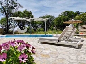 Ein Poolbereich mit Liegestühlen und einer Pergola.