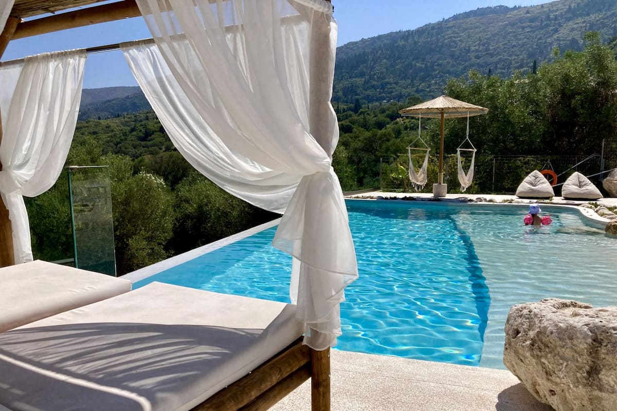 Ein privater Pool mit freiem Blick auf die umliegende Landschaft, ein Himmelbett und eine Lounge-Ecke.