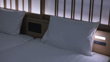 A hotel room with two beds, wooden headboard, and a control panel with a clock.