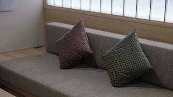 Un sofá con dos almohadas y una ventana con persianas.