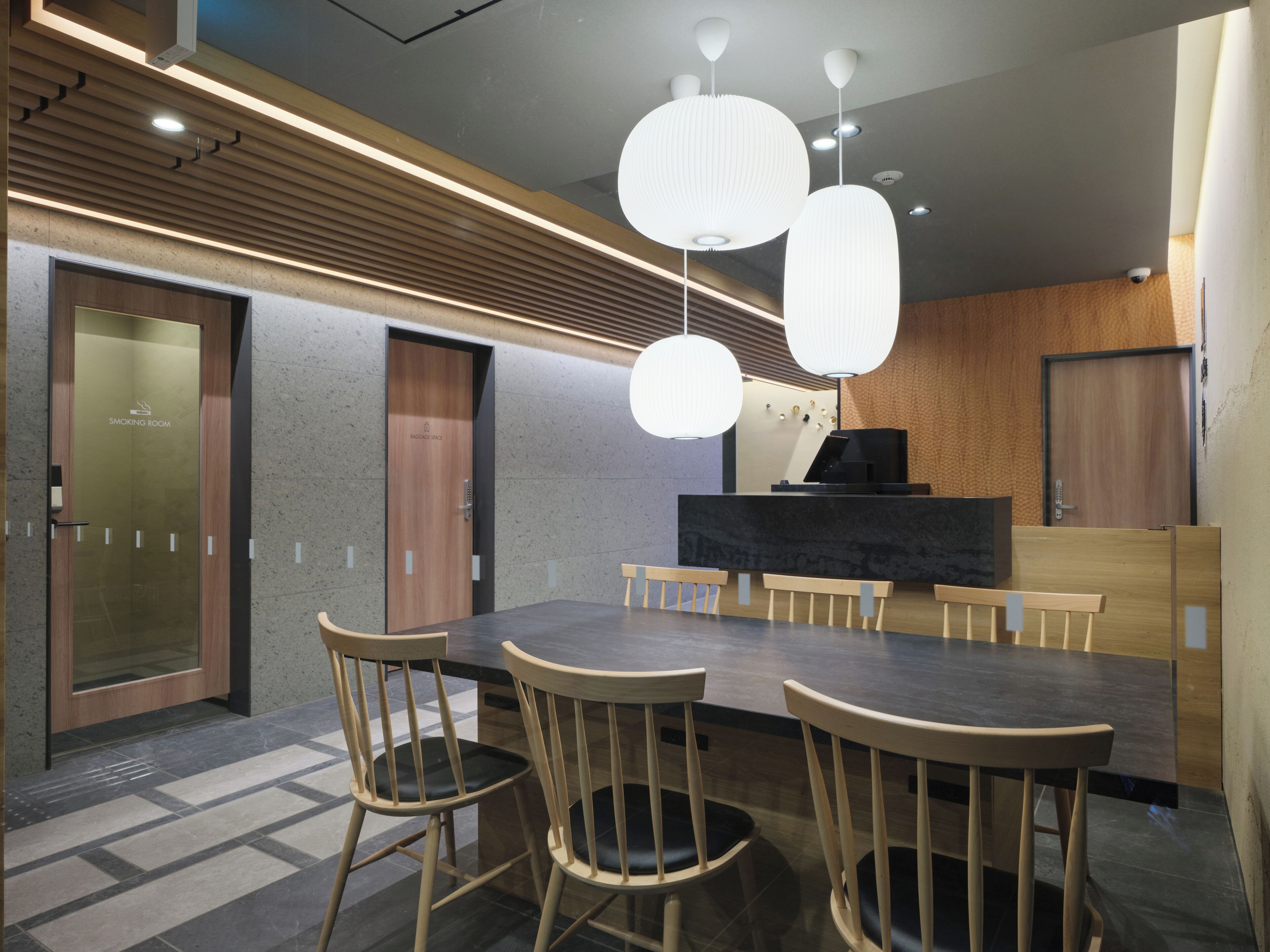 Uma sala de conferências com uma mesa escura, cadeiras de madeira e iluminação pendente.