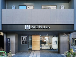 A modern hotel entrance with a prominent 'MONday' sign, a reception desk, and a view of the interior through the glass doors. - Premium Apart MONday HAMAMATSUCHO Station (Tokyo)