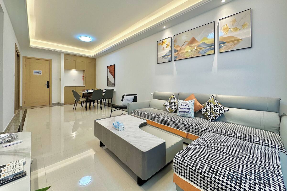 A modern living room with a sofa set, a coffee table, and a dining area with chairs and a table.