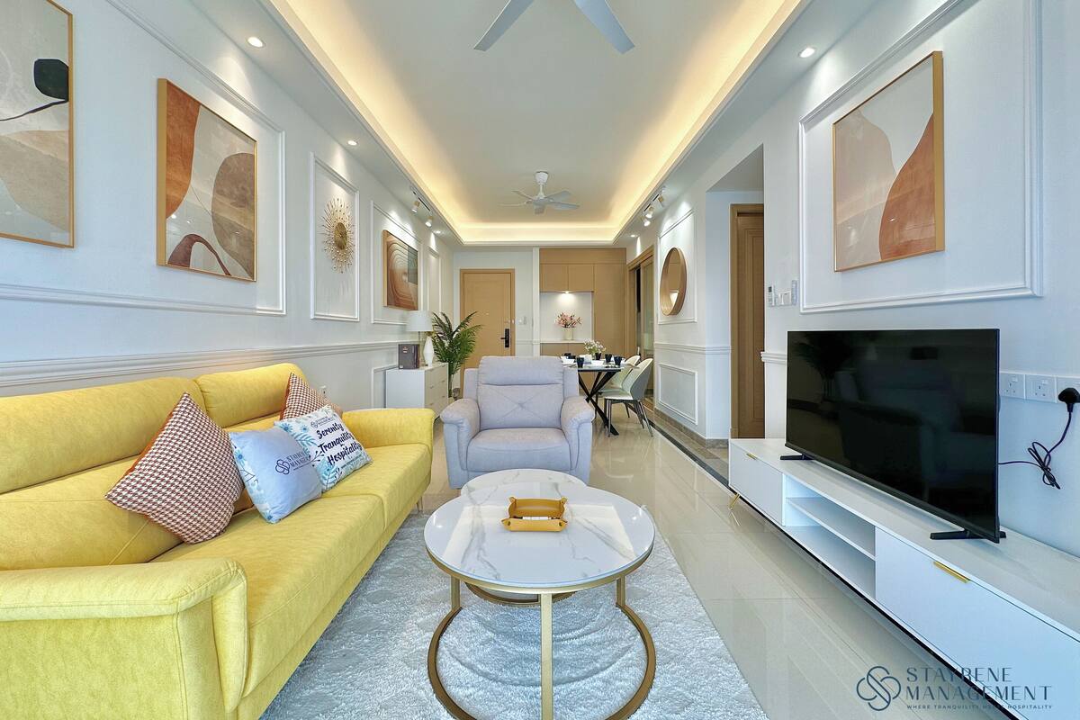 A modern living room with a yellow sofa, a round coffee table, and a flat-screen TV.