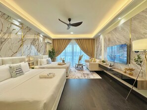 Een moderne hotelkamer met een groot bed, een bank, een televisie en een plafondventilator.