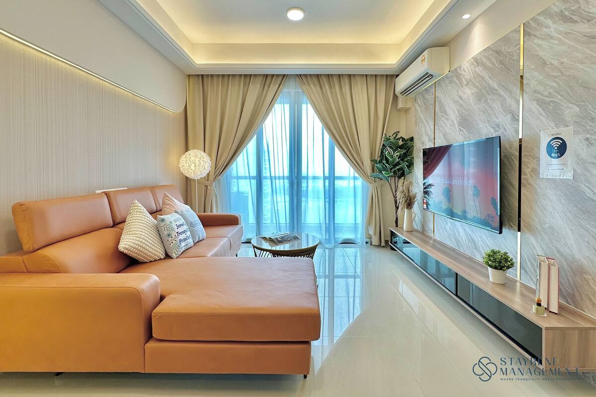 A modern living room with a sofa, a TV mounted on the wall, and a ceiling fan.