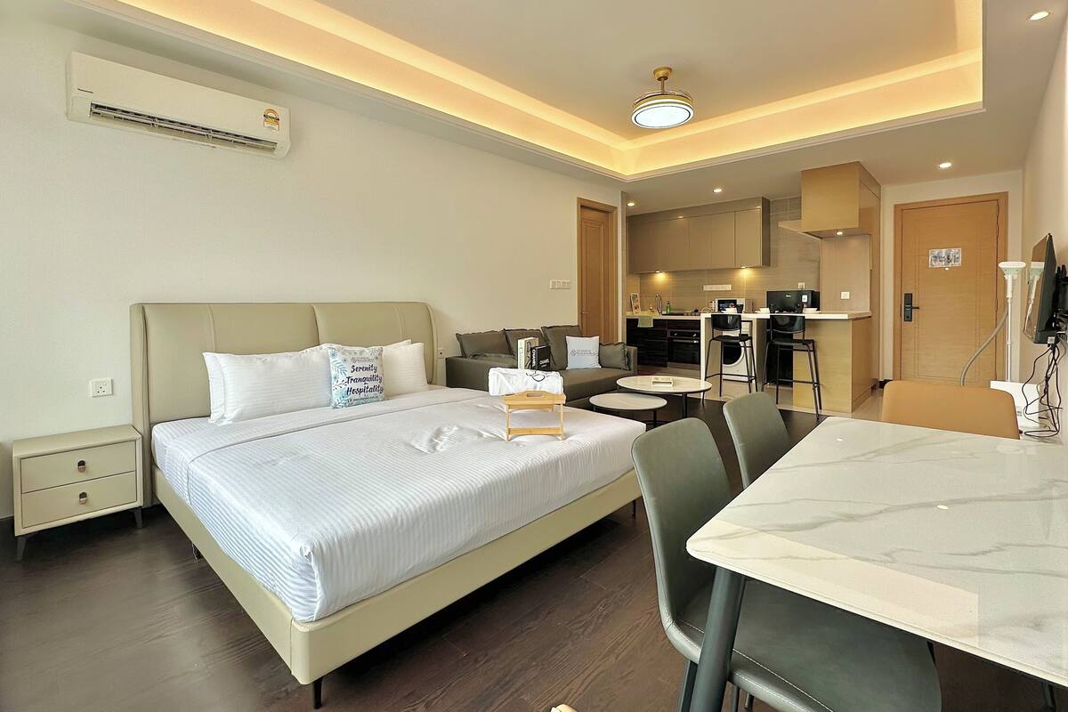 A hotel room with a bed, bedside table, nightstand, and a small seating area with a table and chairs.