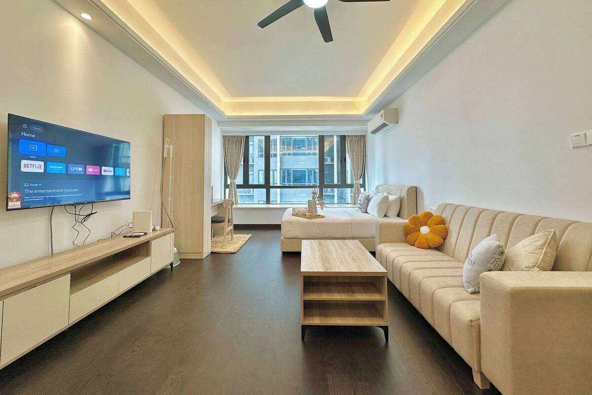 A modern living room with a flat-screen TV, a ceiling fan, a sofa, and a coffee table.