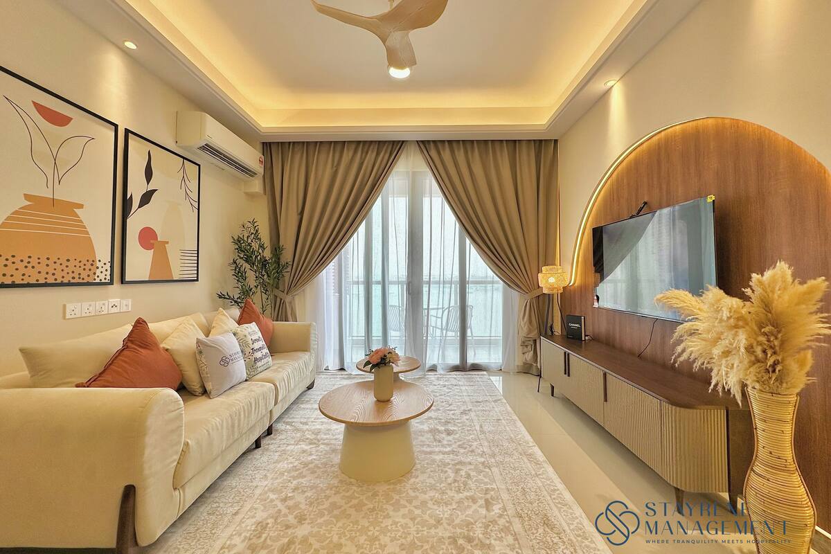 A modern hotel room with a sofa, a coffee table, a TV, and a decorative vase.