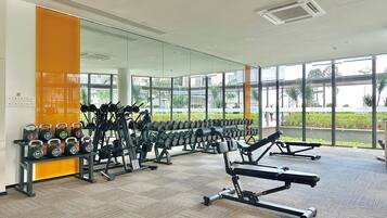 Un gimnasio con equipamiento para levantamiento de pesas, máquinas de ejercicio y un ventanal con vistas al exterior.