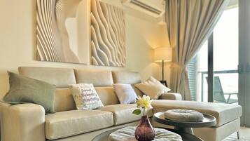 Una sala de estar moderna con un sofá color beige, almohadones decorativos, un jarrón con una flor y una mesa de centro redonda.