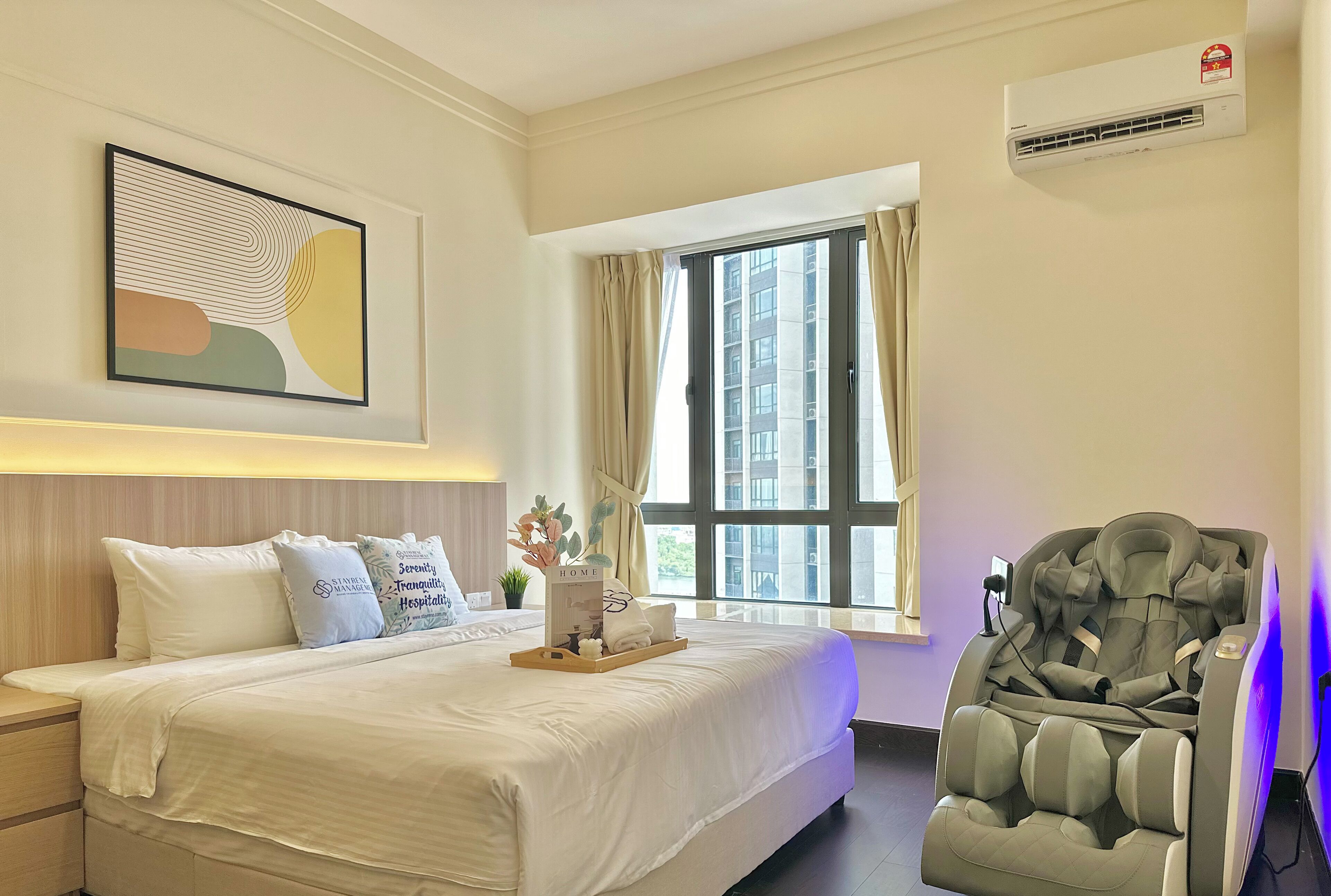 Una camera d'hotel con un letto, una poltrona massaggiante, una finestra con tende, un condizionatore d'aria e un quadro appeso al muro.