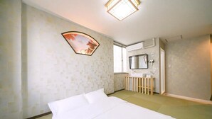 Une chambre d’hôtel avec un lit, une petite table de chevet, un miroir et une fenêtre.