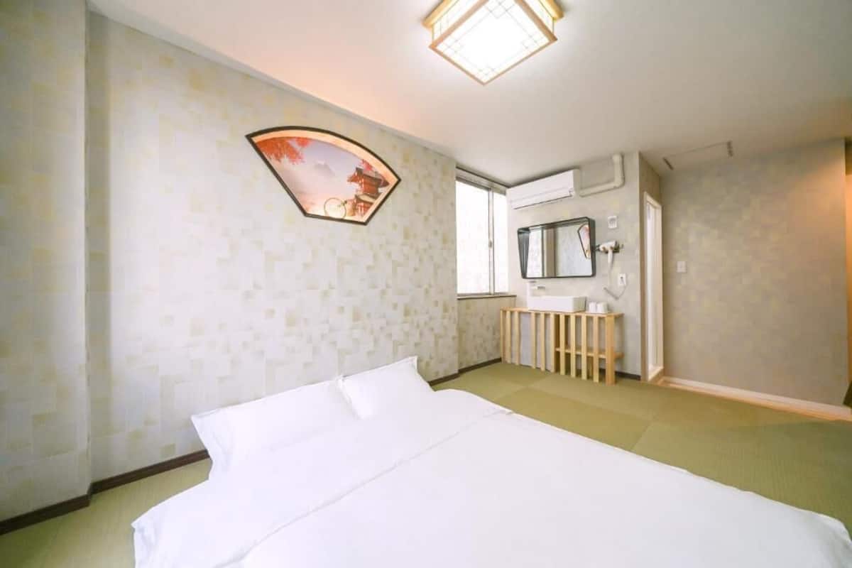 Una habitación de hotel con una cama, una mesita de noche, un espejo y una ventana.