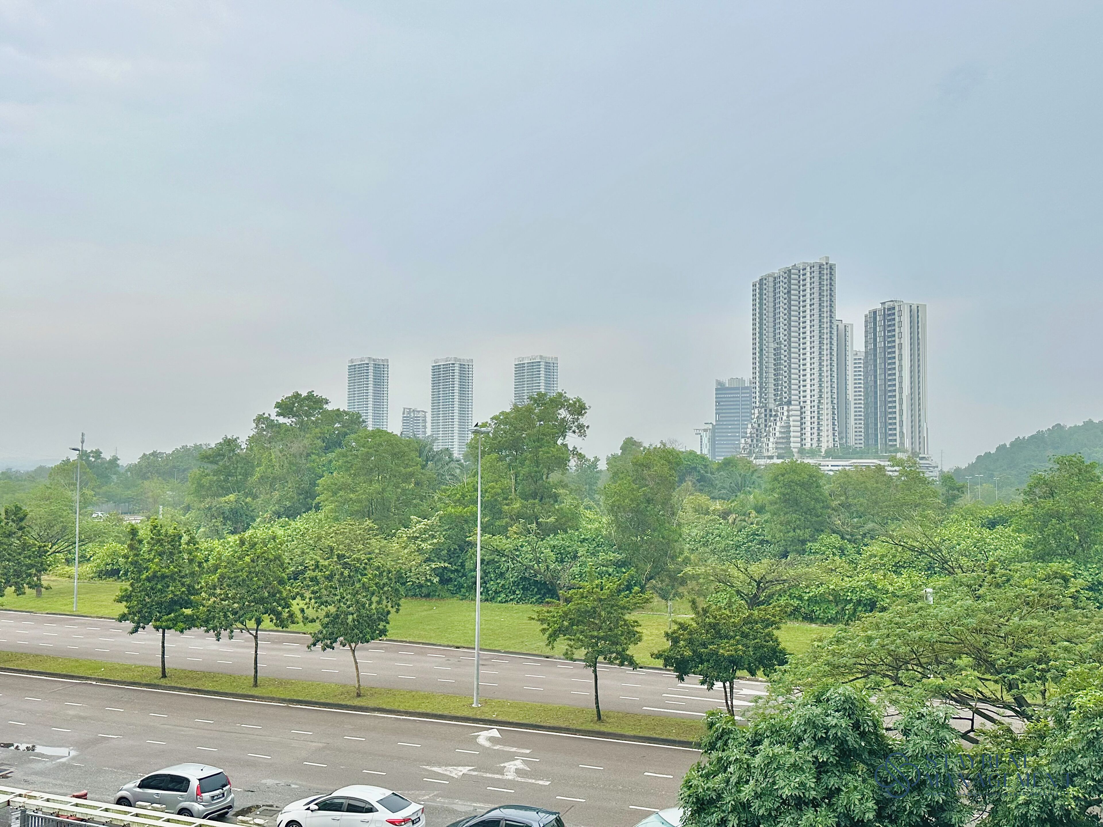 A highway with multiple lanes and cars. There are tall buildings in the background.